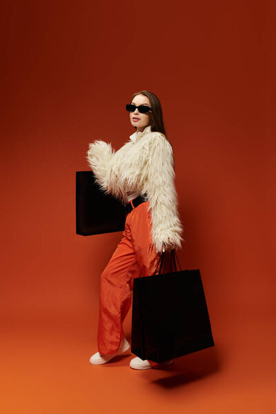 Модная женщина демонстрирует свой яркий стиль, держа в руках сумки, излучая уверенность.