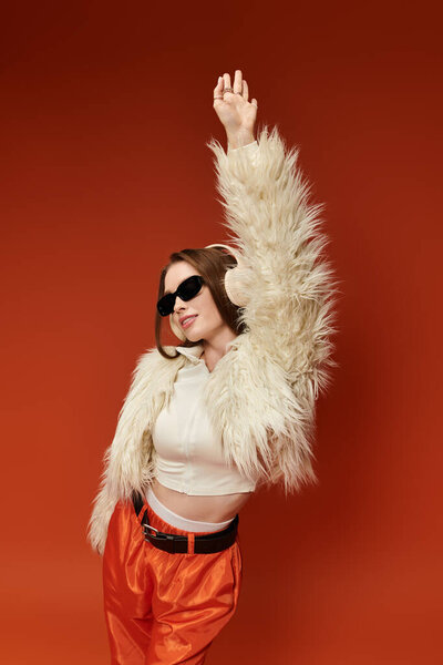 Стильная женщина уверенно позирует в ярком наряде и солнечных очках.