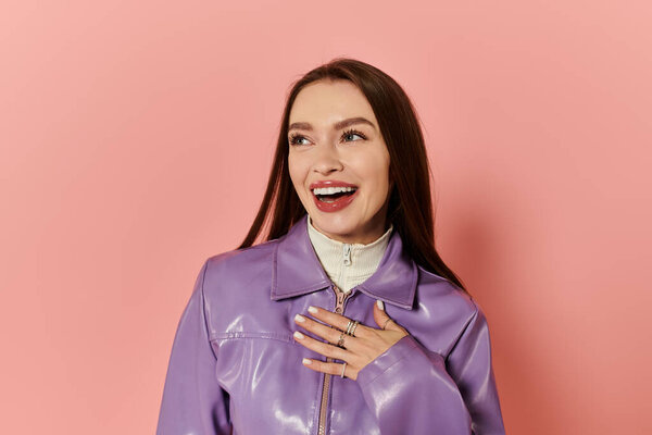 Beautiful woman expresses joy in a purple jacket against a bright pink backdrop.