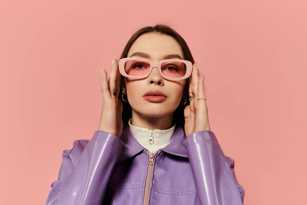 Стильная женщина демонстрирует свою уникальную моду в розовых очках на красочном фоне.