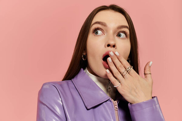A stylish woman with bright hair poses dramatically against a soft pink backdrop.