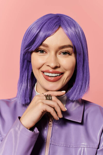 Живая женщина со стильными фиолетовыми волосами и игривой улыбкой стоит на розовом фоне.