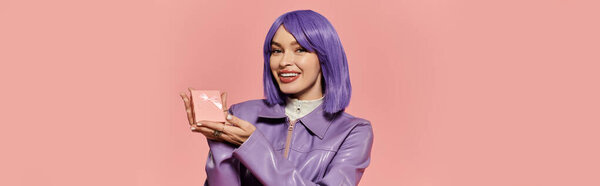 A fashionable woman with purple hair smiles while holding a beauty product in her hands.