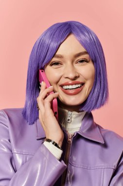 Mor saçlı bir kadın pembe telefonunda neşeyle sohbet ediyor, enerji saçıyor..