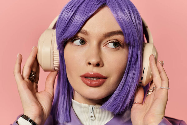 Woman with purple hair enjoys music in stylish headphones against a pink background.