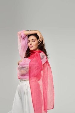 Genç ve güzel bir kadın zarafet sergilerken minimalist bir ortamda renkli bir eşarpla poz veriyor..