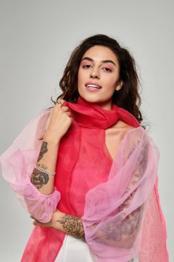 Genç ve güzel bir kadın gülümserken canlı kıyafetini ve benzersiz dövmelerini sergiliyor..