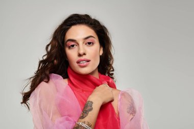 Şık giyinen ve büyüleyici makyajlı güzel genç bir kadın, güvenli bir şekilde içeride poz veriyor..