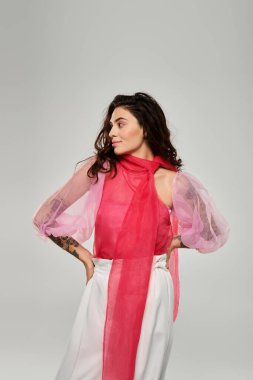 Genç ve güzel bir kadın zarif bir şekilde duruyor, şık kıyafetlerini ve çekiciliğini sergiliyor..