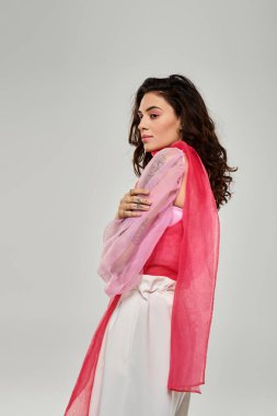 Güzel genç bir kadın sanatsal olarak örtülmüş canlı bir eşarpla moda anlayışını sergiliyor..