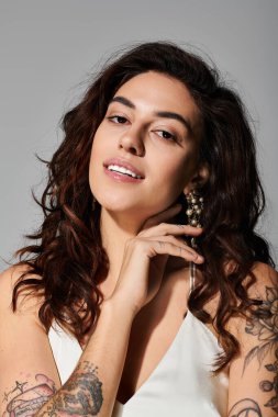 Genç kadın kendine güvenen bir gülümseme ve hafif ışıklandırmada şık aksesuarlarla zarifçe poz veriyor..