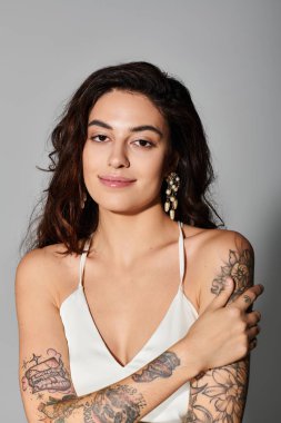 Etkileyici dövmeleri ve zarif küpeleri olan genç ve güzel bir kadın kendinden emin bir görünüm sergiliyor..