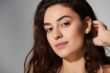 Doğal güzelliği ve uzun saçları olan genç bir kadın çekiciliğini yumuşak bir ışıkta sergiliyor..