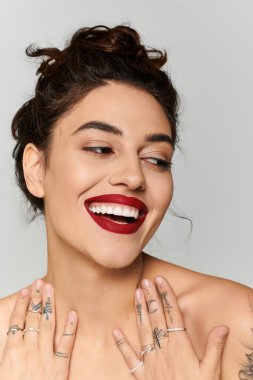Parlak bir gülümsemesi olan güzel genç bir kadın şık yüzüklerini ve şakacı dövmelerini gösteriyor..