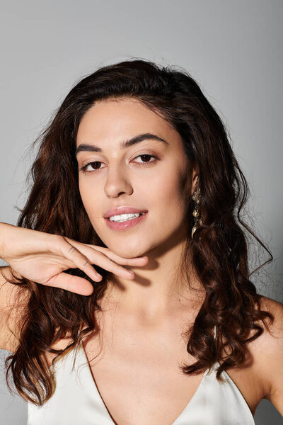 Очаровательная молодая женщина демонстрирует свою красоту с теплой улыбкой на нейтральном фоне.