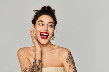 Genç ve güzel bir kadın, neşeli gülümsemesini sergilerken elini yanağında dinlendiriyor..