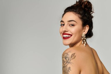 Güzel, genç bir kadın. Mutlu bir şekilde gülümsüyor. Zarif küpelerini ve cazibesini sergiliyor..