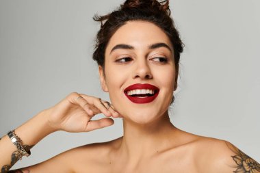 Güzel bir kadın cesur kırmızı dudaklarını, neşeli bir gülümseme ve rahat bir poz vererek sergiliyor..