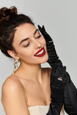 Young beautiful woman showcases her style with elegant gloves and bold red lipstick, smiling. clipart