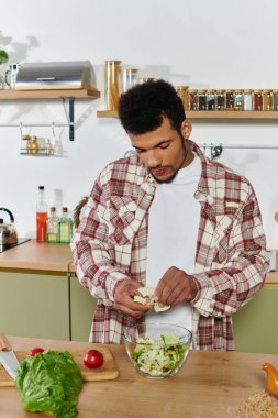 Handsome young man is chopping vegetables for a healthy salad in the kitchen. clipart