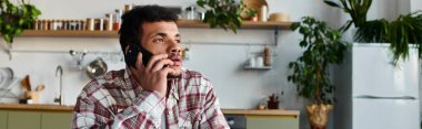 Yakışıklı genç adam parlak bir mutfakta otururken bir telefon görüşmesi yapıyor..