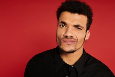 Genç yakışıklı bir adam canlı kırmızı bir arkaplan karşısında neşeli bir ifade sergiliyor..