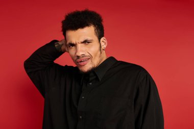 Yakışıklı genç bir adam, eli boynunda, tuhaf bir ifade sergiliyor..