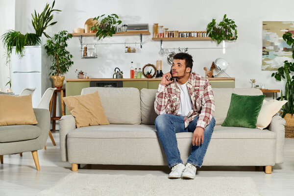 Man sitting comfortably on a sofa, engaged in a phone conversation in a modern living space.