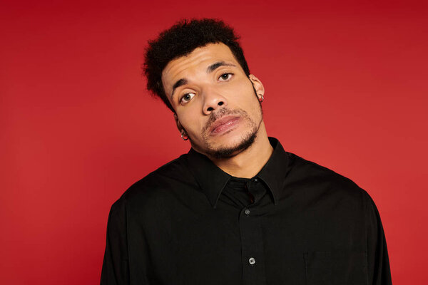 Молодой красивый мужчина стоит с вдумчивым выражением лица, демонстрируя свой стиль в студии.