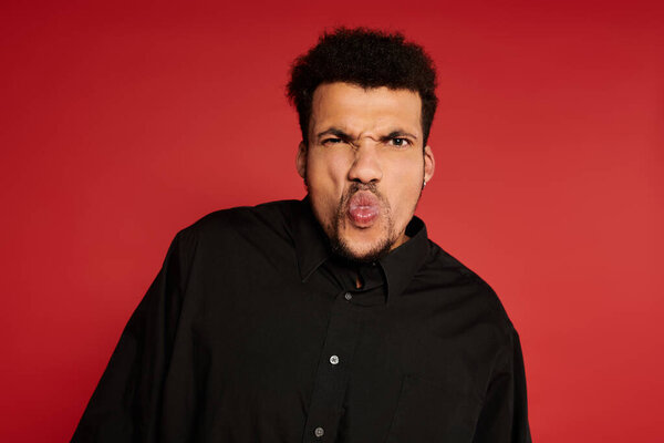 Молодой красивый мужчина показывает игривое выражение лица, позируя перед камерой.