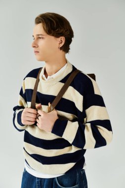 Bu yakışıklı genç adam çizgili bir süveter giyiyor, üniversite maceralarına hazır..