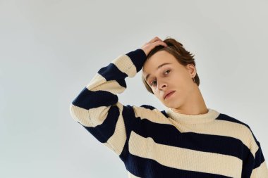 Çizgili süveter giyen genç bir adam üniversite deneyimini stüdyoda yansıtır..