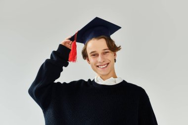 A young man proudly wearing a graduation cap and smiling in a stylish studio setting. clipart