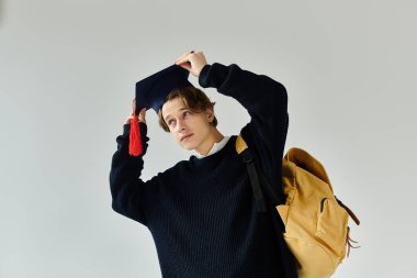 Genç bir adam kolej ruhunu ve gururunu gösterirken mezuniyet şapkasını düzeltiyor..