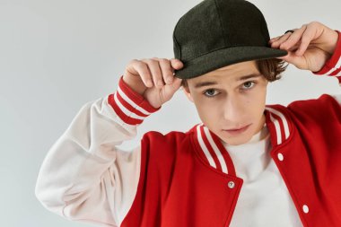 Havalı bomba ceketli yakışıklı genç bir adam yaratıcı stüdyo ortamında şapkasıyla poz veriyor..