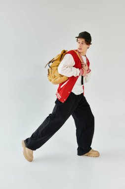 Genç bir adam modaya uygun bir bombacı ceketi ve stüdyo ortamında rahat bir şekilde poz veriyor..