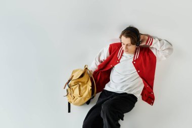 Genç bir adam şık bir stüdyoda bombardıman ceketi giyer ve müzik dinler..