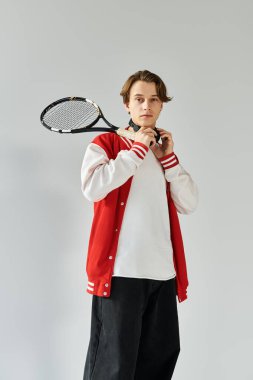 Moda bombardıman ceketli kendine güvenen genç adam yaratıcı bir mekanda tenis raketiyle poz veriyor..