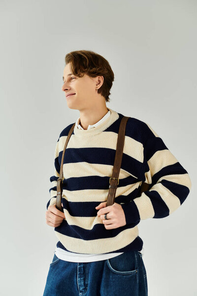 Красивый молодой человек демонстрирует свой стиль в полосатом свитере, захватывая момент уверенности.