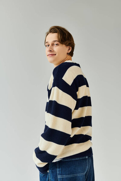 Молодой человек в стильном полосатом свитере тепло улыбается, олицетворяя молодость и дух колледжа.