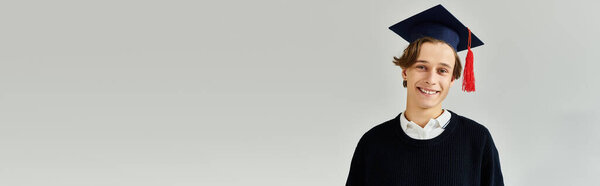 Молодой человек в шапке выпускника гордо улыбается в студии во время своих студенческих лет, баннер