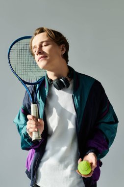 Confident student holds a tennis racket and ball, showcasing his sporty style and youthful energy. clipart