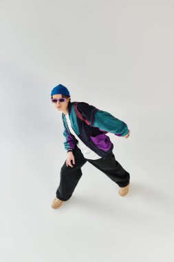 Stüdyoda poz verirken şık bir ceketle moda anlayışını sergileyen genç bir adam..