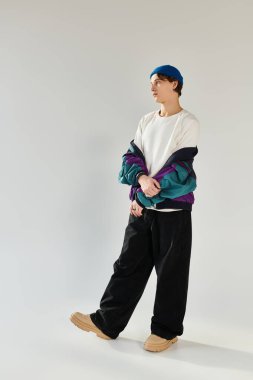 Havalı bombardıman ceketli genç öğrenci minimalist bir stüdyoda düşünceli bir şekilde poz veriyor..