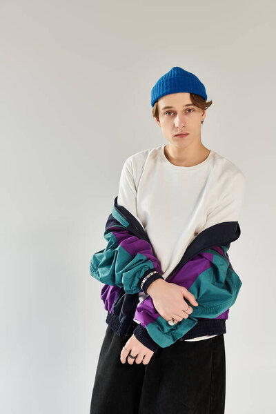 A young man showcases his trendy bomber jacket while posing in a modern studio space.