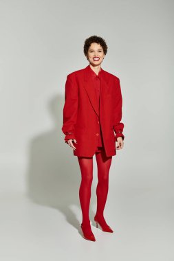 Genç bir kadın şık bir stüdyoda cesur bir kırmızı elbiseyle kendinden emin bir şekilde sallanıyor..