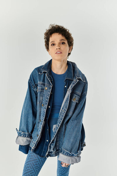 Молодая красивая женщина изящно позирует в непринужденном, но шикарном наряде, излучая уверенность.