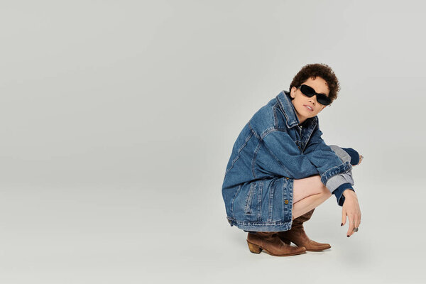 A confident young woman with short hair poses stylishly, radiating uniqueness.