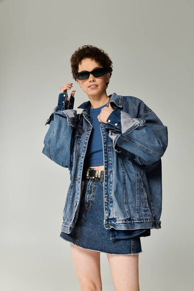 Молодая женщина демонстрирует свою моду с жирными огромными джинсами и шикарными аксессуарами.