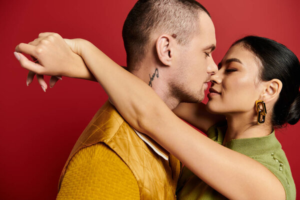 Прекрасная молодая пара наслаждается интимным моментом в стильной одежде на ярком фоне.